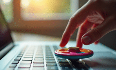 Main faisant tourner un fidget spinner coloré sur un clavier d'ordinateur